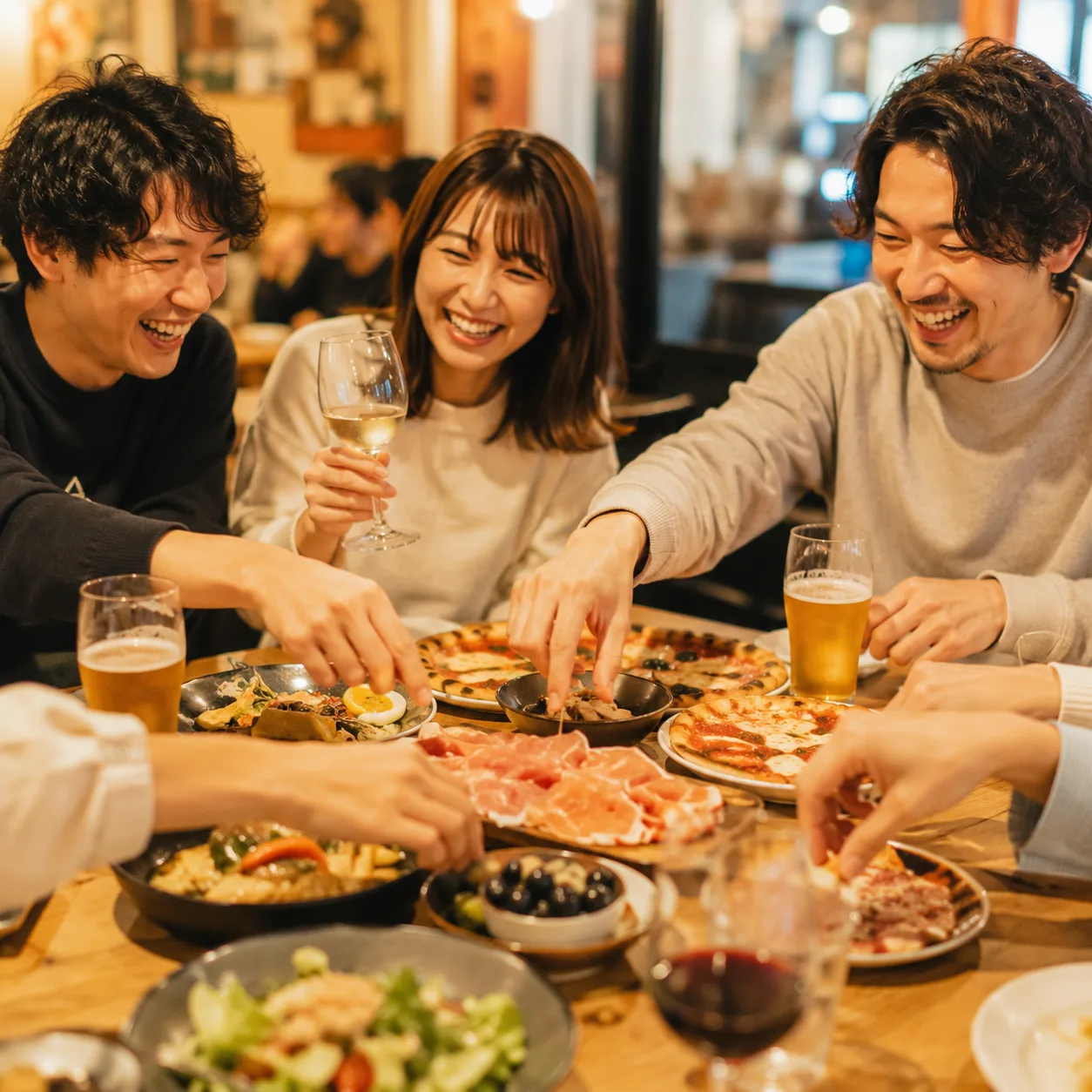 ご友人との食事のイメージ。テーブルを囲んでにぎやかに楽しむ食事シーン